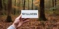 Motivational inspiring hand holding word card stillness in woods