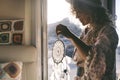 Wanderlust lifestyle people. One woman holding dreamcather decoration on the door of her mobile home with outdoors and sunset time