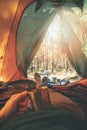 Wanderlust - man relaxing in tent after hike with cup of tea