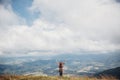 wanderlust and travel concept. girl traveler in hat with backpack raising hands up in mountains. stylish hipster woman on top Royalty Free Stock Photo