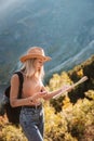 Wanderlust and travel concept. Stylish traveler girl in hat looking at map, exploring woods