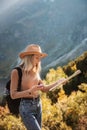 Wanderlust and travel concept. Stylish traveler girl in hat looking at map, exploring woods