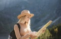 Wanderlust and travel concept. Stylish traveler girl in hat looking at map, exploring woods