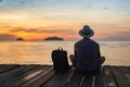 wanderlust travel, tourist with backpack sitting near the sea, man enjoying sunset, solo traveler Royalty Free Stock Photo