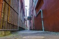 Narrow alleyway between city old buildings with services pipes and signs