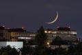 Waning Crescent Moon setting over urban cityscape after dusk