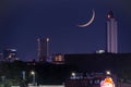 Waning Crescent Moon setting over urban cityscape after dusk