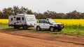 Wannamal, WA, Australia - Aug 22, 2020: A modern 4WD caravan parked on a dirt back road next to a field of bright yellow Canola on