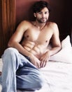 Want to join me. Sexy young man lying bare-chested on a bed - portrait. Royalty Free Stock Photo