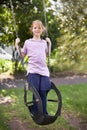 Want to see how high Ill go. Cute little girl standing on a swing in a garden. Royalty Free Stock Photo