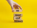 We want your feedback symbol. Wooden blocks with words We want your feedback. Beautiful yellow background. Businessman hand. We