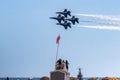 Four US Navy Blue Angels Jets flying in formation over a lifeguard stand at the beach during an airshow