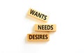 Wants needs and desires symbol. Concept words Wants Needs Desires on wooden blocks. Beautiful white table white background.