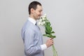 He wants to give a flowers. Side view portrait of charming pleasure romantic young man in blue shirt holding bouquet of white flow Royalty Free Stock Photo