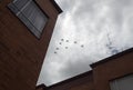 War airplanes in V formation flying over a residential unit with cloudy grey sky Royalty Free Stock Photo