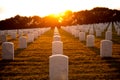 War cemetery with rows of white marble graves on green grass at sunset with ocean view. Marine veteran's cemetery Royalty Free Stock Photo