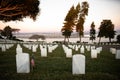 War cemetery with rows of white marble graves on green grass at sunset with ocean view. Marine veteran's cemetery Royalty Free Stock Photo