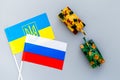 War, confrontation concept. Russia, Ukraine. Tanks toy near russian and Ukrainianflag on grey background top view