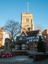 War Memorial with wreaths of red poppies at the foot, with historic Tudor building and Pinner Parish Church behind. Pinner UK Royalty Free Stock Photo