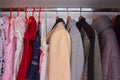 A wardrobe with clothes,summer children`s dresses and autumn and winter clothes for adults hang on a shelf in the closet Royalty Free Stock Photo