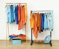 Wardrobe with complementary colors orange and blue clothes on hangers.