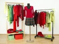 Wardrobe with complementary colors red and green clothes arranged on hangers.