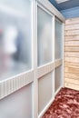 Wardrobe with matte glass on sliding door near wooden wall