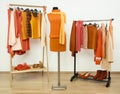 Wardrobe with orange clothes arranged on hangers and an autumn outfit on a mannequin.