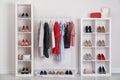 Wardrobe shelves with different stylish shoes and clothes indoors