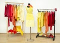 Wardrobe with yellow, orange and red clothes arranged on hangers.