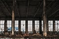 Warehouse with big windows, columns and debris of abandoned and ruined industrial factory building interior Royalty Free Stock Photo