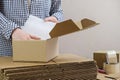 Warehouse employee packs the order of the online store in a cardboard box