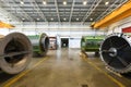 Warehouse of a factory with heavy cranes on roof rails, large mechanical parts and concrete floors