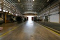 Warehouse of a factory with heavy cranes on roof rails, large mechanical parts and concrete floors