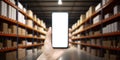 Warehouse with a hand holding an empty smartphone. Blurred industrial warehouse with goods and products. Logistics Royalty Free Stock Photo