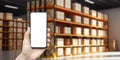 Warehouse with a hand holding an empty smartphone. Blurred industrial warehouse with goods and products. Logistics Royalty Free Stock Photo