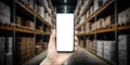 Warehouse with a hand holding an empty smartphone. Blurred industrial warehouse with goods and products. Logistics Royalty Free Stock Photo