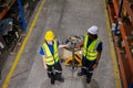 Warehouse industrial stock storage, man and woman worker wear safety uniform push load cart product to shelf in warehouse store. Royalty Free Stock Photo