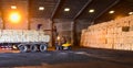 Warehouse intake, forklift lift-off sugar bags from truck to stack inside a warehouse. Sugar, grain, food, rice, maize, cargo.