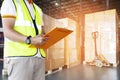 Warehouse inventory management, Warehouse worker holding clipboard checking shipment boxes in warehouse storage. Royalty Free Stock Photo