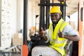 Warehouse man worker driver forklift. warehouse worker driver stacking card boxes by forklift in warehouse store. African American Royalty Free Stock Photo