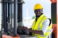 Warehouse man worker driver forklift. warehouse worker driver stacking card boxes by forklift in warehouse store. African American Royalty Free Stock Photo