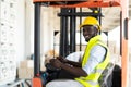 Warehouse man worker driver forklift. warehouse worker driver stacking card boxes by forklift in warehouse store. African American Royalty Free Stock Photo