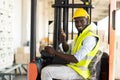 Warehouse man worker driver forklift. warehouse worker driver stacking card boxes by forklift in warehouse store. African American