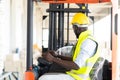 Warehouse man worker driver forklift. warehouse worker driver stacking card boxes by forklift in warehouse store. African American Royalty Free Stock Photo