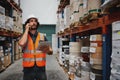 Warehouse manager tracking supply order details using digital tablet while in conversation over mobile phone in Royalty Free Stock Photo