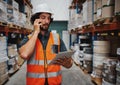 Warehouse manager tracking supply order details using digital tablet while in conversation over mobile phone in Royalty Free Stock Photo