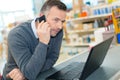 Warehouse manager using telephone and laptop at desk Royalty Free Stock Photo
