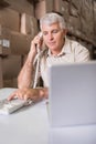 Warehouse manager using telephone and laptop Royalty Free Stock Photo