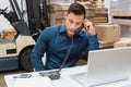 Warehouse manager using telephone and laptop Royalty Free Stock Photo